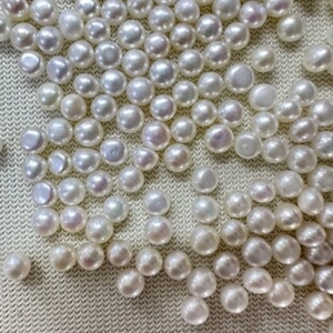 Macro shot of natural white and pink freshwater pearls on textured knit background