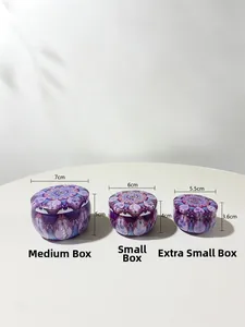 Three sizes of metal candle tins with purple mandala patterns on a white table