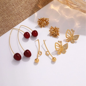 Golden earrings collection featuring cherry charms, butterflies, and geometric designs