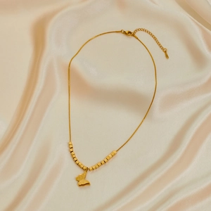 Collar de mariposa dorada con cuentas mates sobre una elegante tela de seda champán