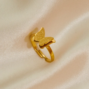 Detalle de anillo de mariposa dorado con alas mate sobre un fondo de seda elegante