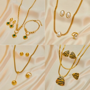Cuatro estilos de conjuntos de joyas de acero dorado con collares sobre seda champán