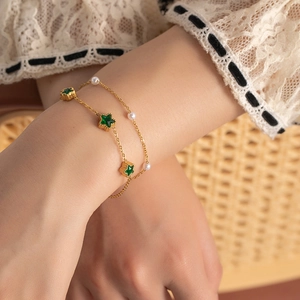 Double-layer titanium steel bracelet with green stars and pearls on a female wrist