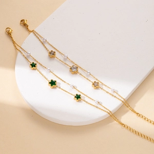 Detail of double-layer gold chain bracelet with star gems and small white pearls