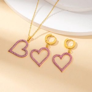 Golden heart-shaped jewelry set with pink rhinestones featuring a necklace and hoop earrings