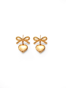 Close-up of gold bow and heart stud earrings with a polished metallic finish