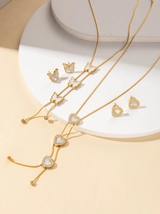 Dettaglio del set gioielli in oro con farfalla e cuore e inserti in madreperla lucida