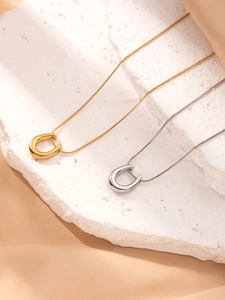Detailed view of polished gold and silver U-shaped pendant necklaces on a stone surface