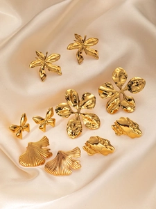 Gros plan de boucles d'oreilles papillon et ginkgo dorées sur tissu en soie