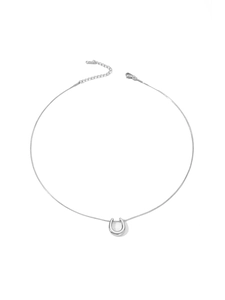 Detailed macro view of a silver U-shaped horseshoe pendant on a thin snake chain