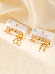 Detailed macro view of two gold stainless steel earring sets with heart and snake charms