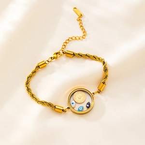 Detail of gold rope chain bracelet with evil eye charms and coin on silk fabric