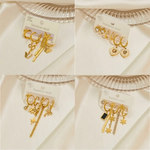 Gold stainless steel earring set featuring heart, star, and butterfly charms on silk fabric