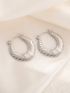 Macro-opname van zilveren titanium stalen oorbellen met elegante geplooide golfstructuur