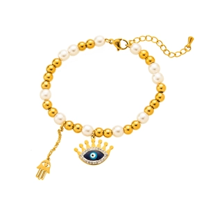 Detail of beaded bracelet featuring gold beads, pearls, evil eye and Hamsa hand charms