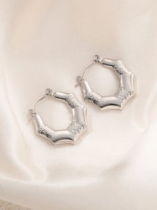 Detail van zilveren titanium stalen oorringen met geometrische schubbentextuur