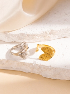 Dettaglio di anelli a foglia vintage oro e argento su pietra con sfondo in seta