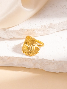 Dettaglio di un anello vintage dorato in acciaio inossidabile con texture di foglie e piume