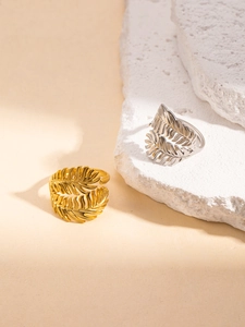 Close-up of gold and silver feather rings with adjustable open band and detailed texture