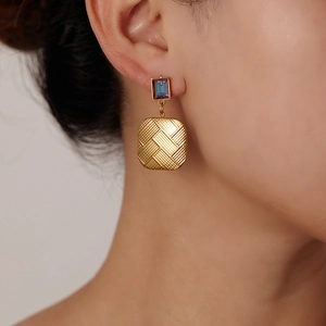 Detailed close-up of retro 18K gold butterfly earrings with woven texture and purple gems
