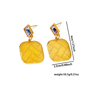 Detail view of gold butterfly earrings with purple gems and geometric textured patterns
