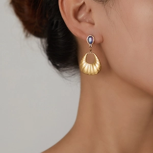 Detail of vintage gold butterfly earrings with purple pear-shaped stone and fan fringe