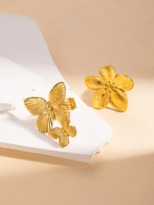 Detail of gold titanium steel rings with textured butterfly and floral motifs on stone