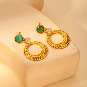 Detail of 18K gold hammered ring earrings featuring green cat's eye stone inlay