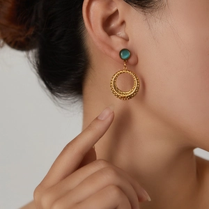 Close-up of retro gold earrings with blue cat-eye stone and hammered texture hoops