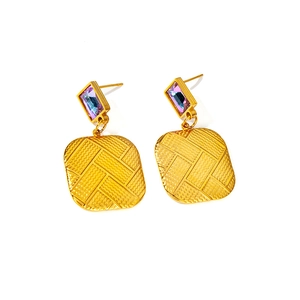Detailed macro of 18K gold plated drop earrings with purple crystal and woven metal texture