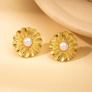 Detailansicht goldener unregelmäßiger Blumenohrringe mit Perlen auf beige Fläche