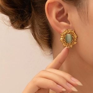 Detalle de pendientes vintage dorados con piedra ojo de gato verde en modelo