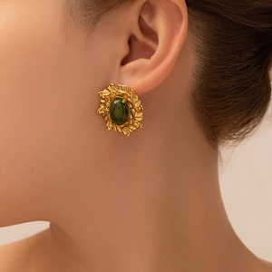 Detalle de pendiente retro dorado con resina verde de estilo vintage puesto en oreja