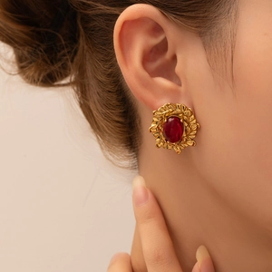 Detalle de los pendientes retro de corona dorada con piedras preciosas rojas ovaladas