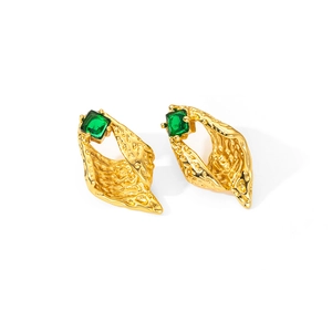 Vista detallada de pendientes de caracola dorados con circón verde y textura martillada