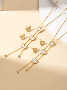 Dettaglio del set collana dorata con ciondoli a forma di cuore e farfalla bianca