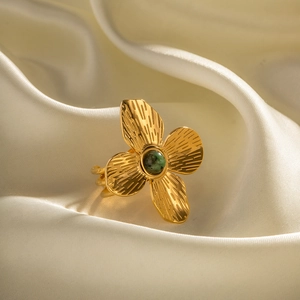 Gold flower open ring with green stone inlay and textured petals on silk backdrop