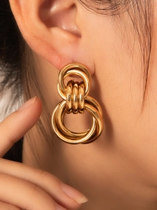 Detalle macro de pendientes de aro entrelazados bañados en oro en la modelo
