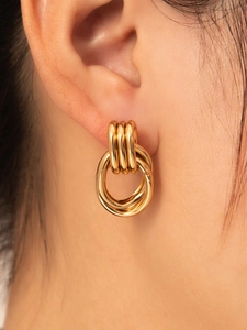 Vista macro de pendientes de aro triples dorados pulidos en oreja de modelo