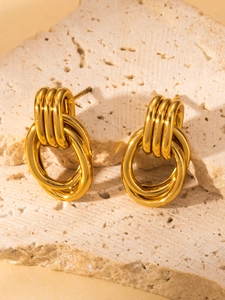 Detalle de pendientes dorados vintage multicapa sobre fondo de piedra natural
