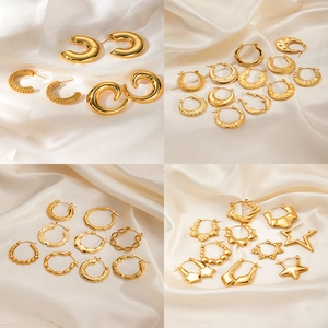 Set of gold stainless steel hoop earrings with star motifs on cream silk background