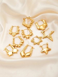 Detail view of assorted gold star and textured earrings on champagne silk fabric