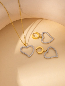 Close-up of a gold heart jewelry set featuring a necklace and stud earrings with pavé stones