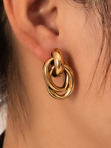 Primer plano de pendientes de aro triples dorados en la oreja de una modelo
