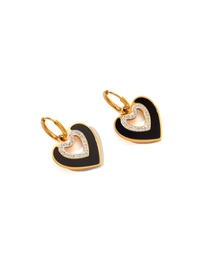 Close-up of heart-shaped gold earrings with black enamel and sparkling zircon detail