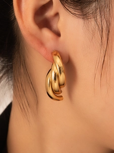 Vista macro lateral de pendientes gruesos de oro con acabado pulido en la oreja del modelo