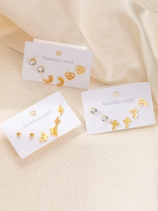 Détail de l'ensemble de boucles d'oreilles en acier doré avec cœur, papillon et éclair