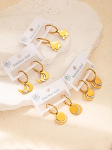 Détail de boucles d'oreilles en acier avec charms étoile et cœur en or et argent