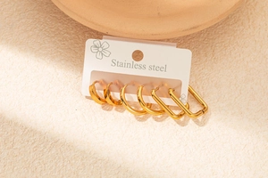 Détail de quatre paires de boucles d'oreilles créoles en acier doré sur carte