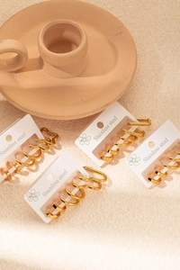 Ensemble détaillé de boucles d'oreilles créoles en acier doré sur cartes sur fond esthétique